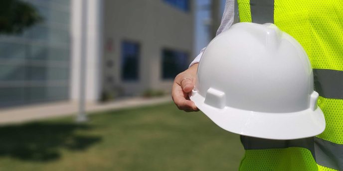 A closeup of someone in a hi-vis jacket holding a hard hat - Retrofit West Trusted Trades