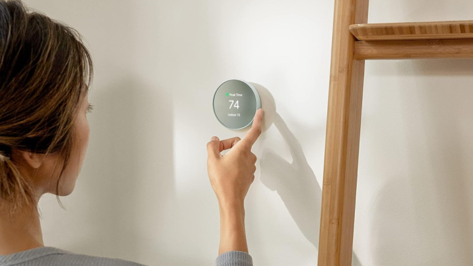woman adjusting a round thermostat unit on the wall