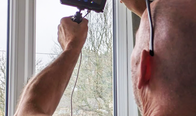 Man with thermal imaging camera examining the window for air leaks