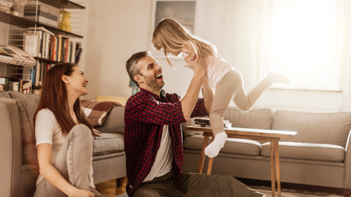 family playing with their child in a sunny living room