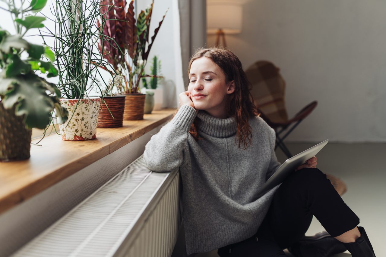 Woman reclining next to window and windowsill with green plants - Retrofit West