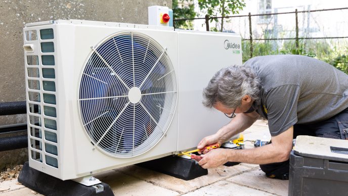 Man fitting a heat pump outdoors