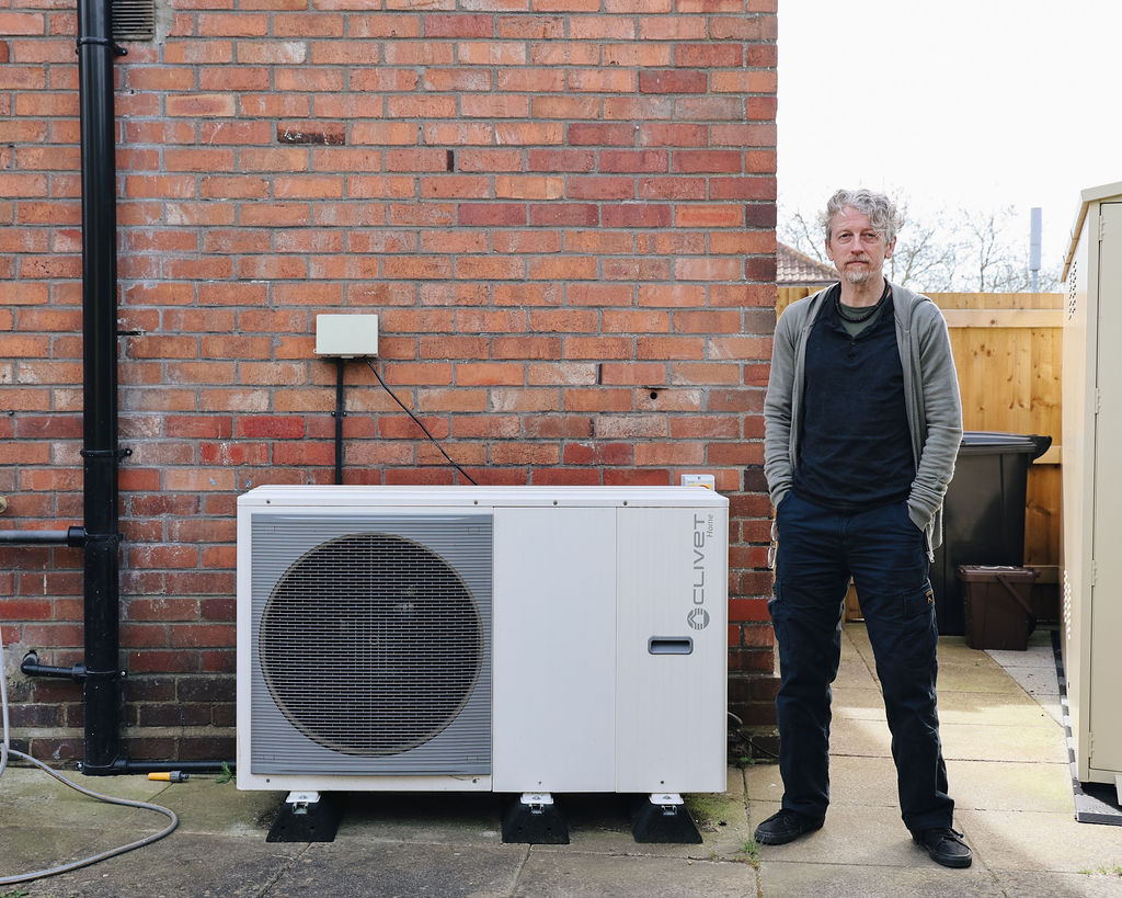 Kirk standing next to his heat pump outside his home