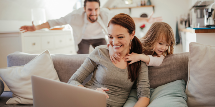 family playing and smiling whilst looking at laptop