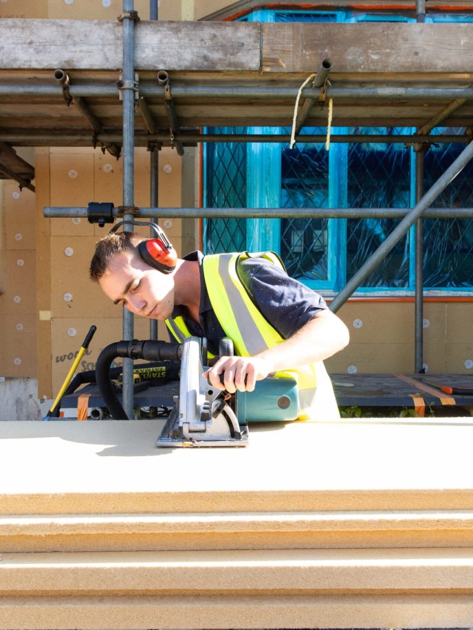 cutting insulation boards with a jigsaw outside a house