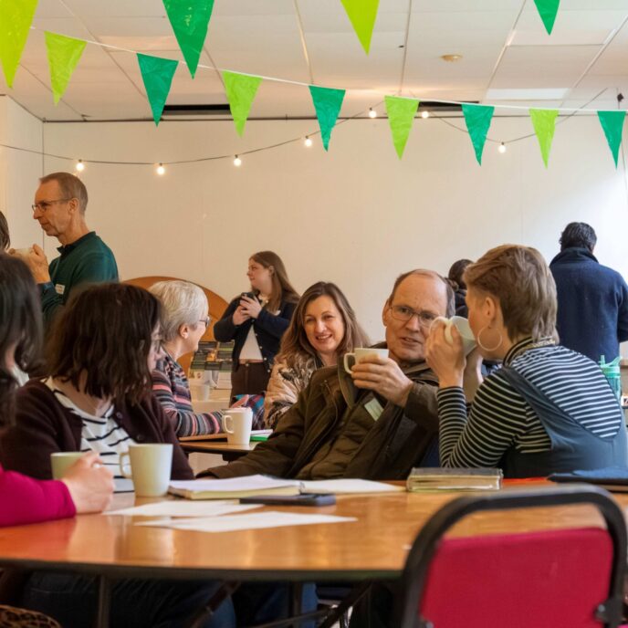 People having informal conversations at a community event. Chatting over cups of tea.