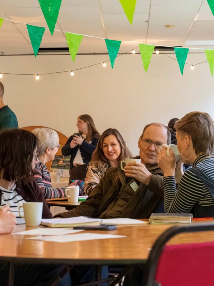 People having informal conversations at a community event. Chatting over cups of tea.