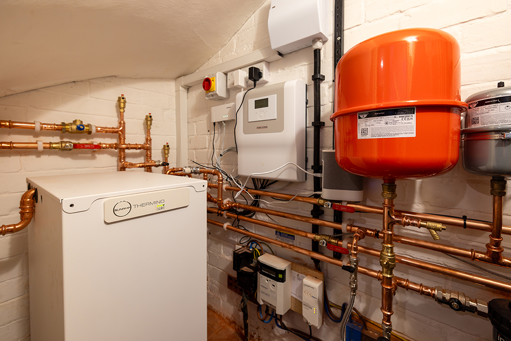 SunAmp thermino and orange hot water cylinder in room with copper pipes